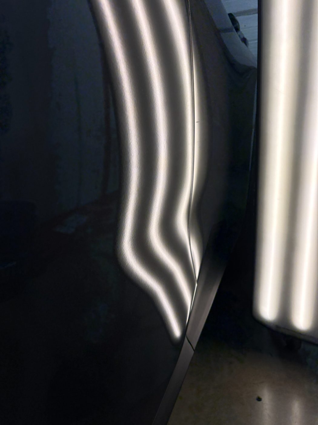 Reflection lines bending over a dent in a Lincoln door before paintless dent repair